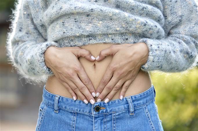mujer haciendo corazón con las manos sobre el abdomen