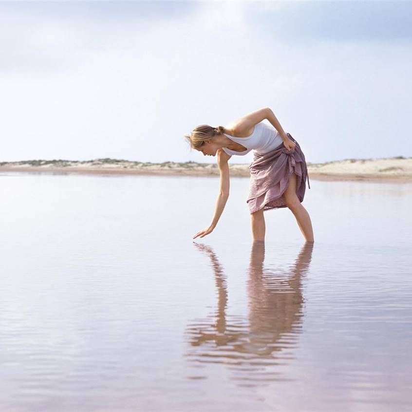 Mujer agachada en el mar