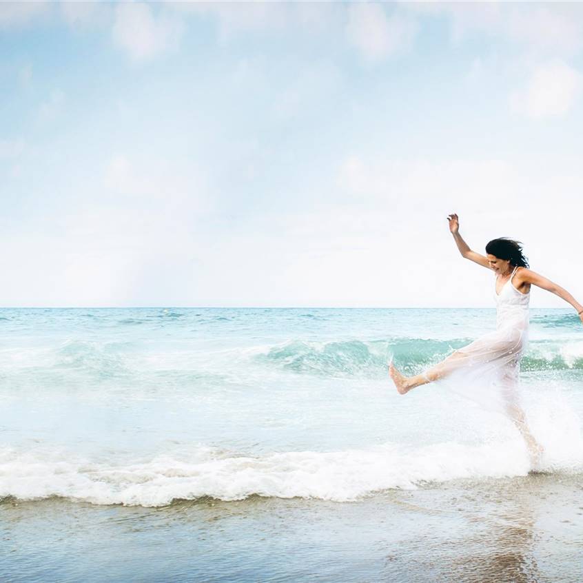 Mujer saltando en la playa