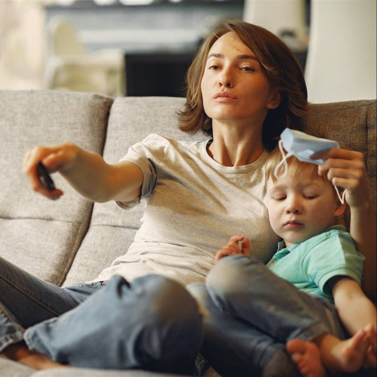 Mujer con su hijo en el sofá con mascarilla en la mano