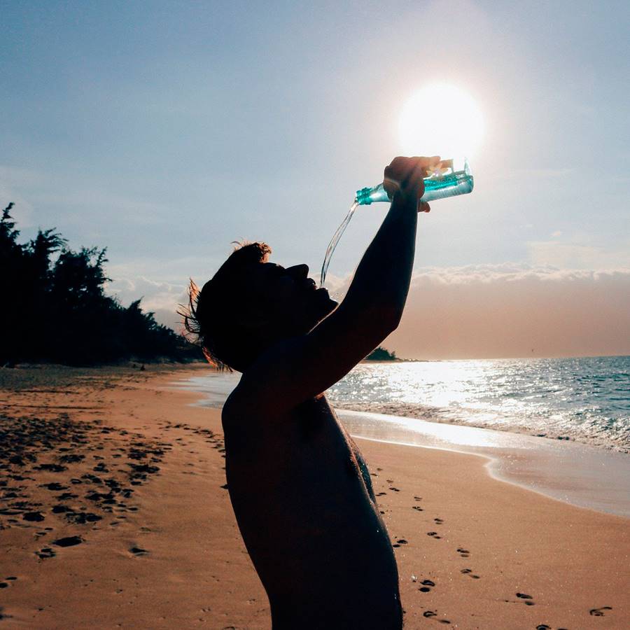 chico playa bebiendo sol