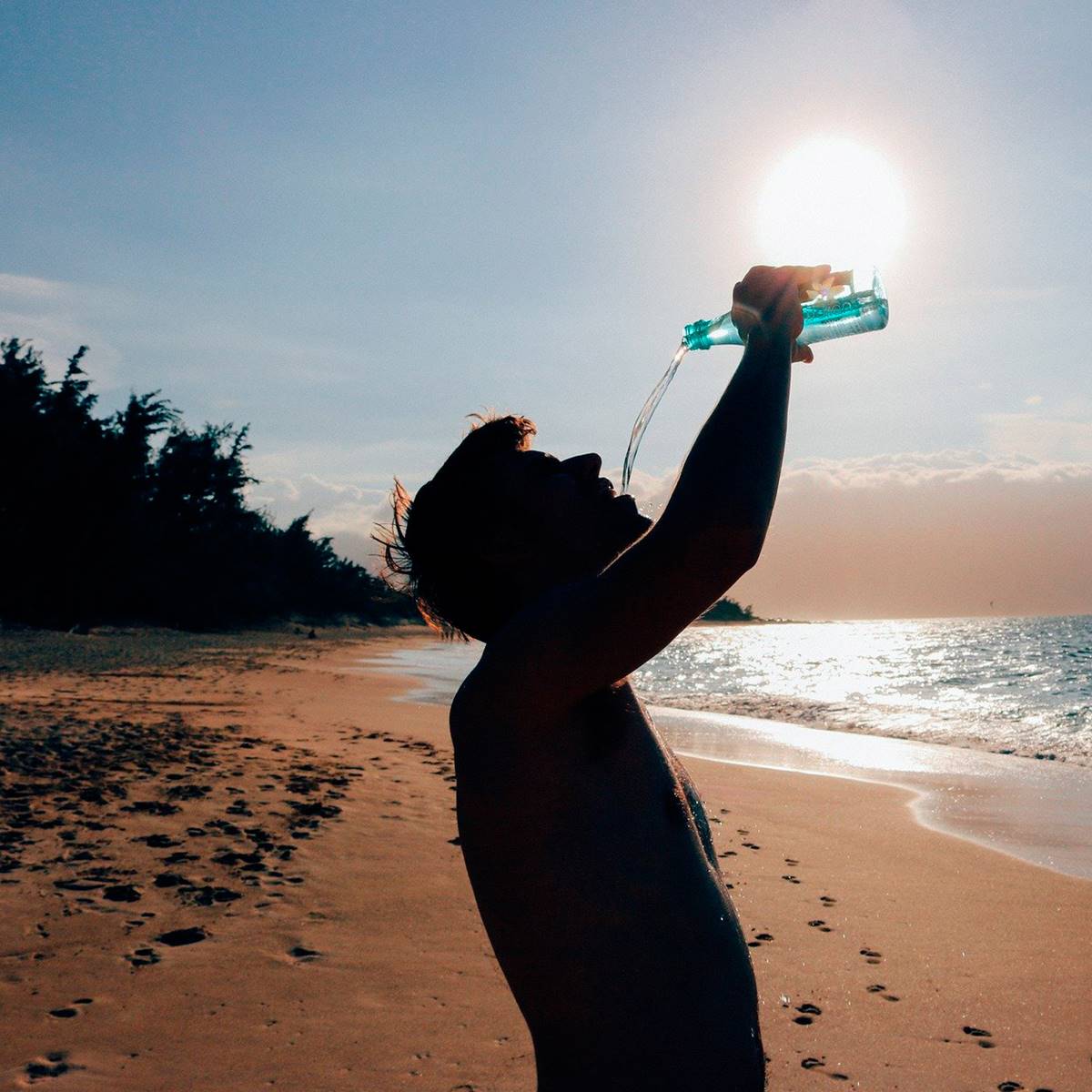 chico playa bebiendo sol