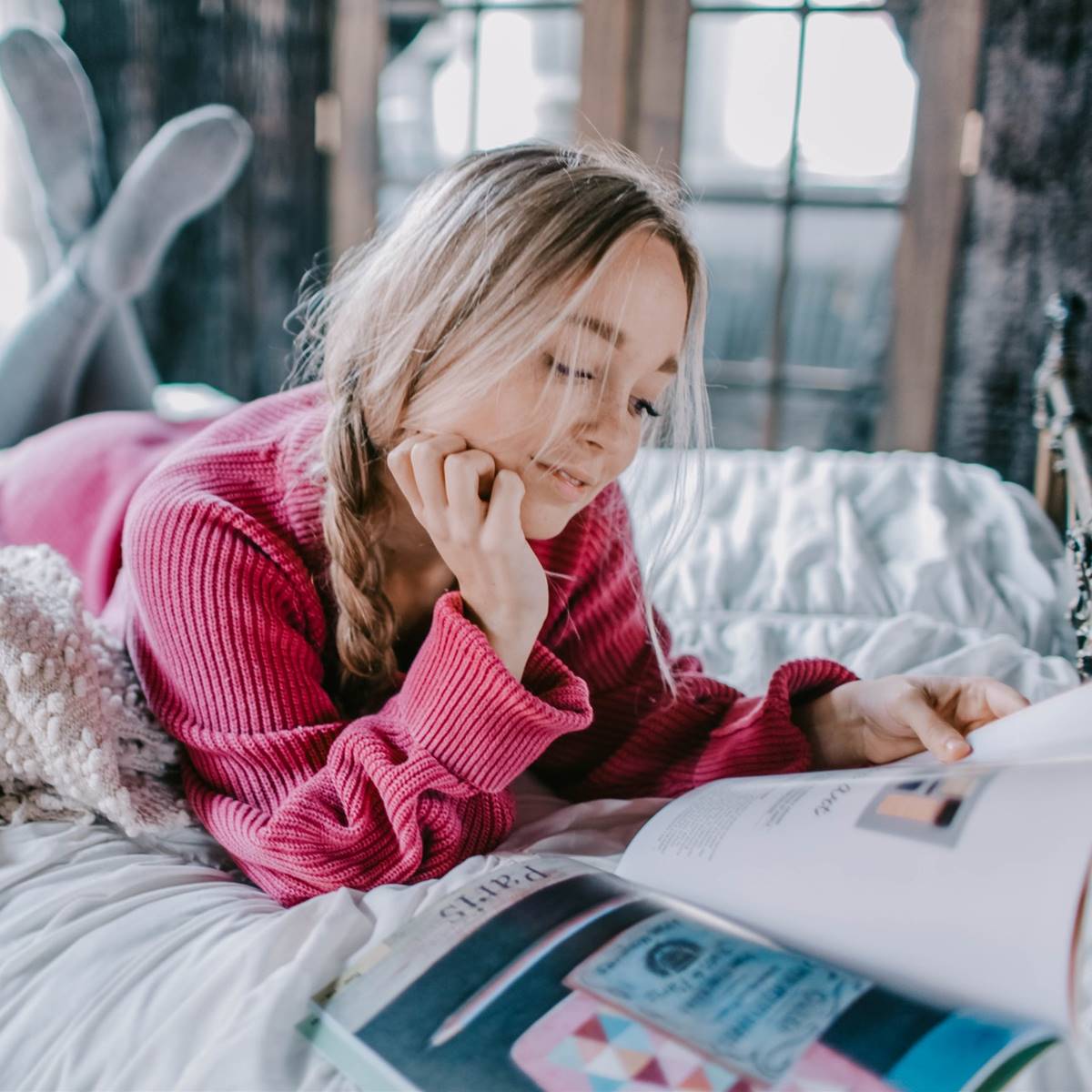 Chica leyendo una revista en la cama