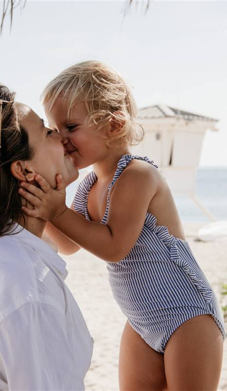Niña en la playa besando a su madre