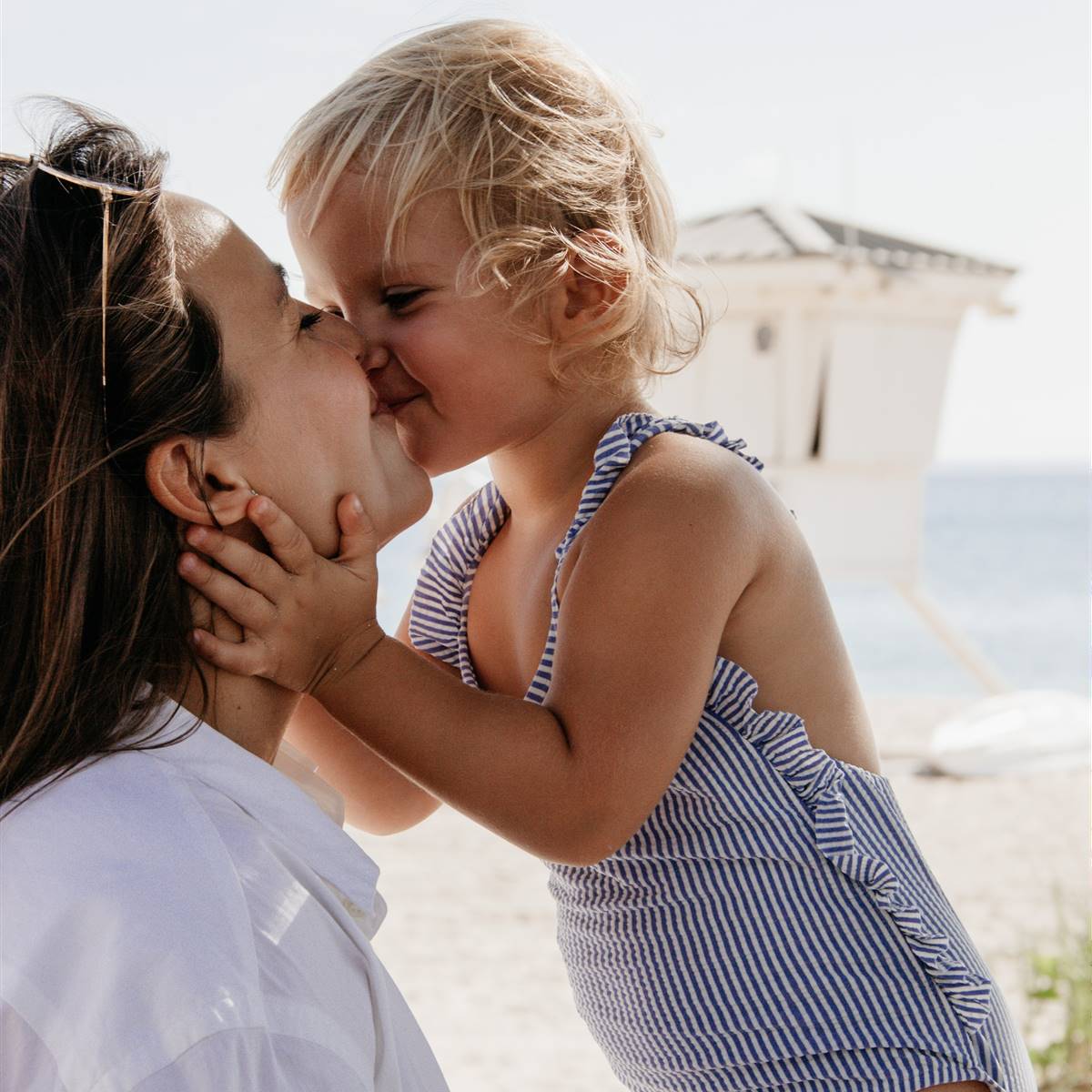 Niña en la playa besando a su madre