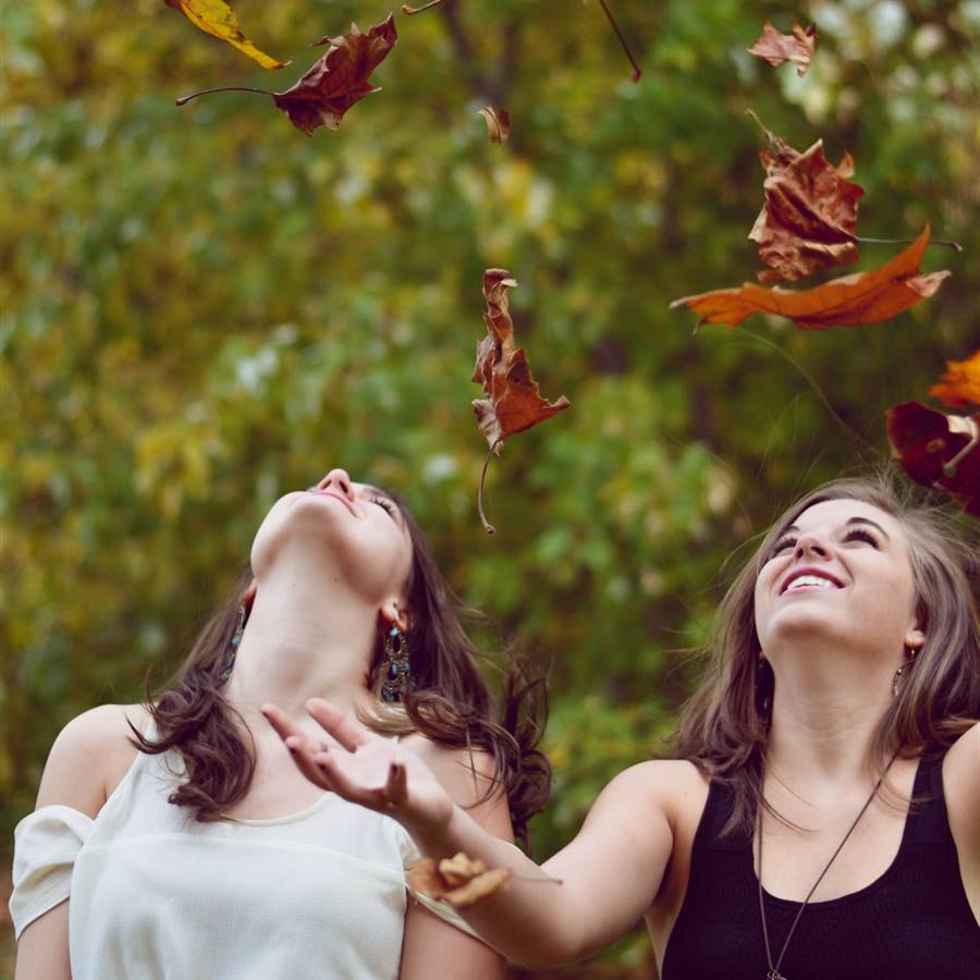 Chicas tirando al aire hojas secas