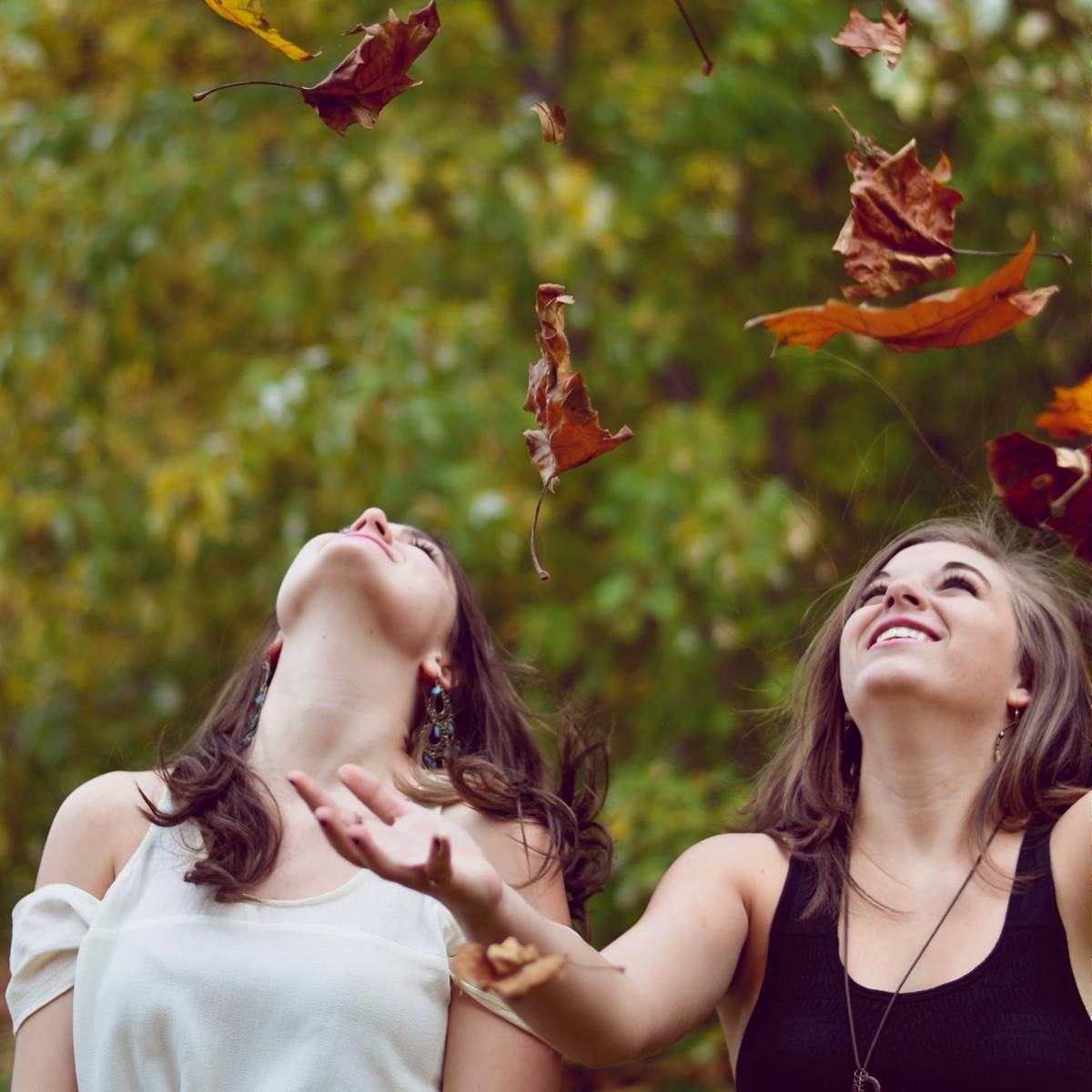 Chicas tirando al aire hojas secas