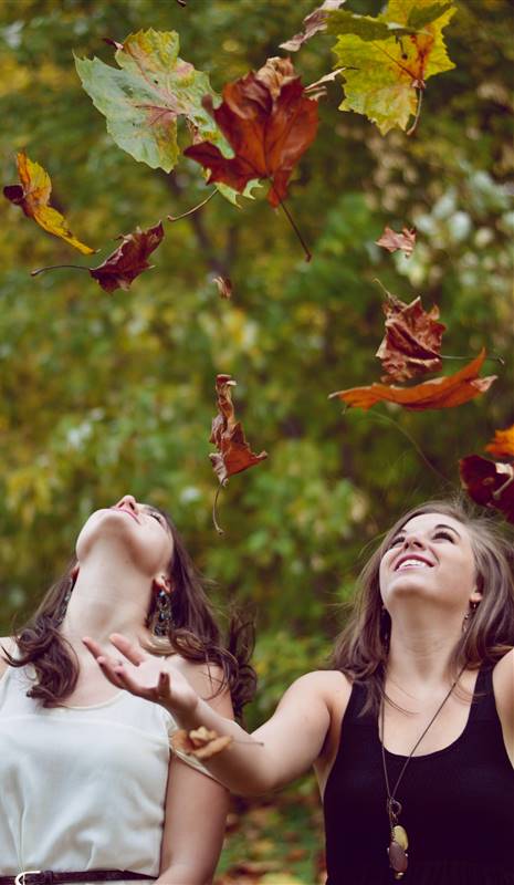 Chicas tirando al aire hojas secas