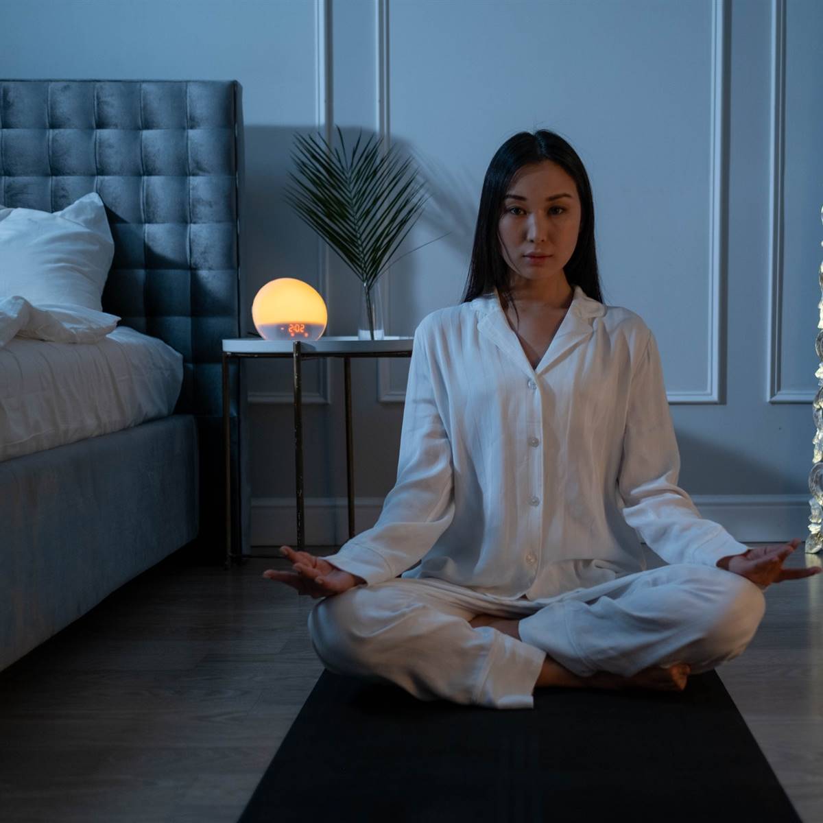 Mujer asiática en la posición del loto en un dormitorio oscuro