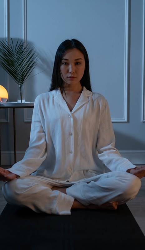Mujer asiática en la posición del loto en un dormitorio oscuro