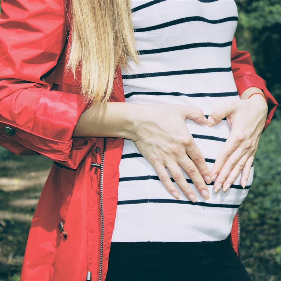 Barriga de embarazada con camiseta marinera y parka rojo