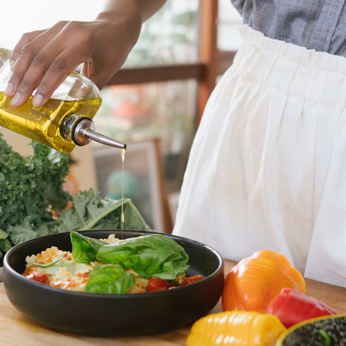 Mujer aliñando una ensalada con aceite de oliva