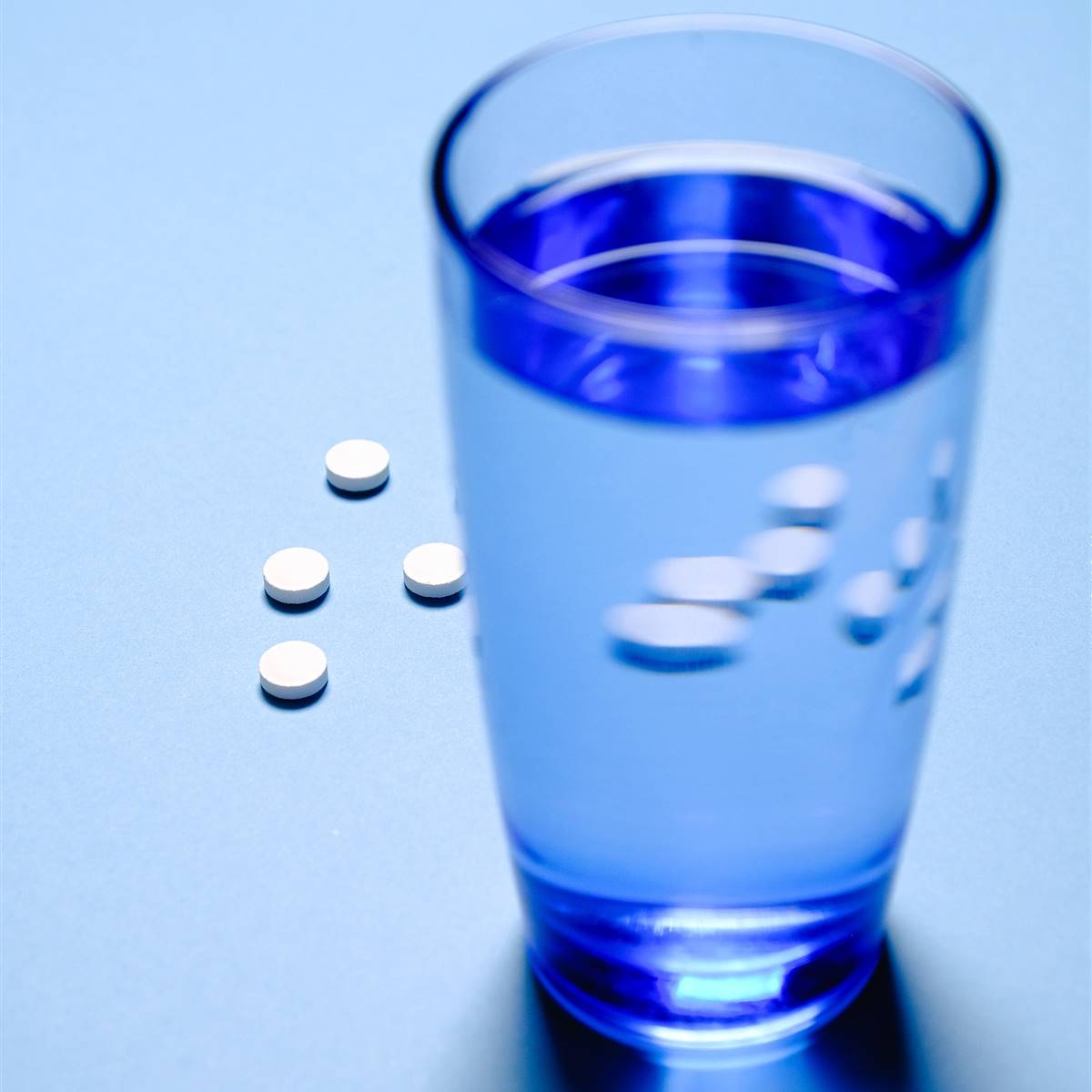 Vaso de agua con pastillas alrededor