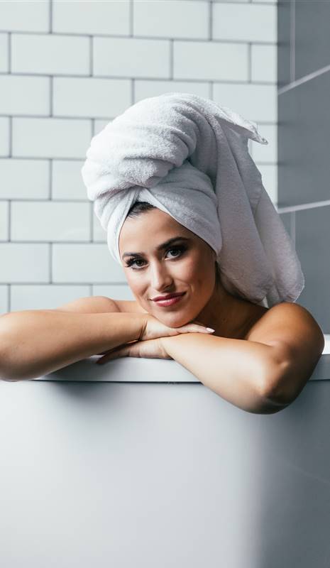 Mujer en la bañera con toalla enrollada en la cabeza