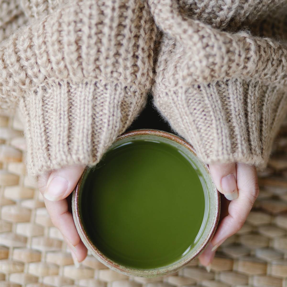 Manos de mujer sosteniendo un tazón de té verde