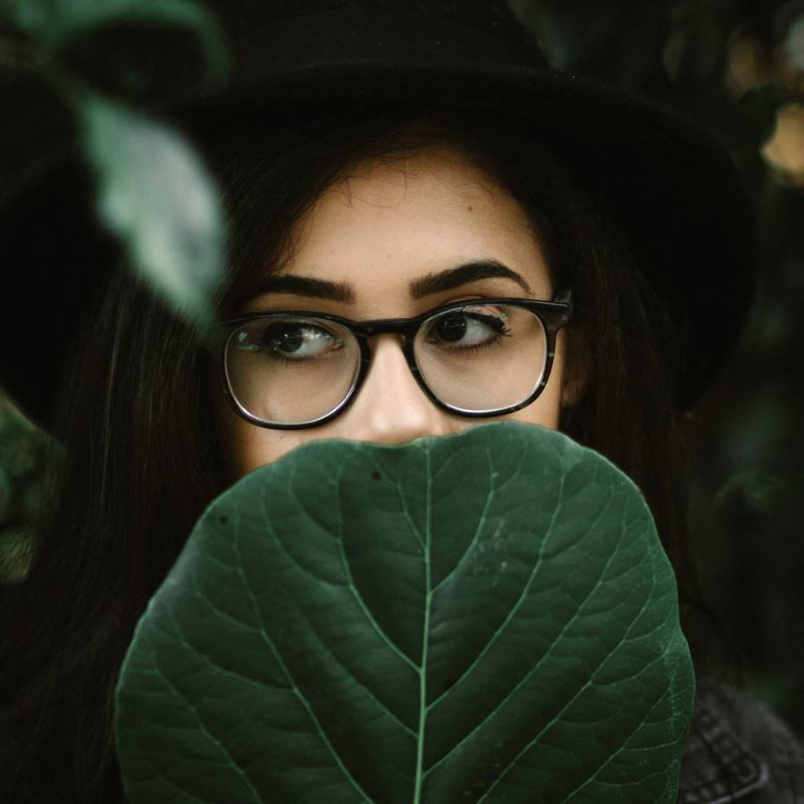 Chica con gafas medio tapada con una hoja de árbol