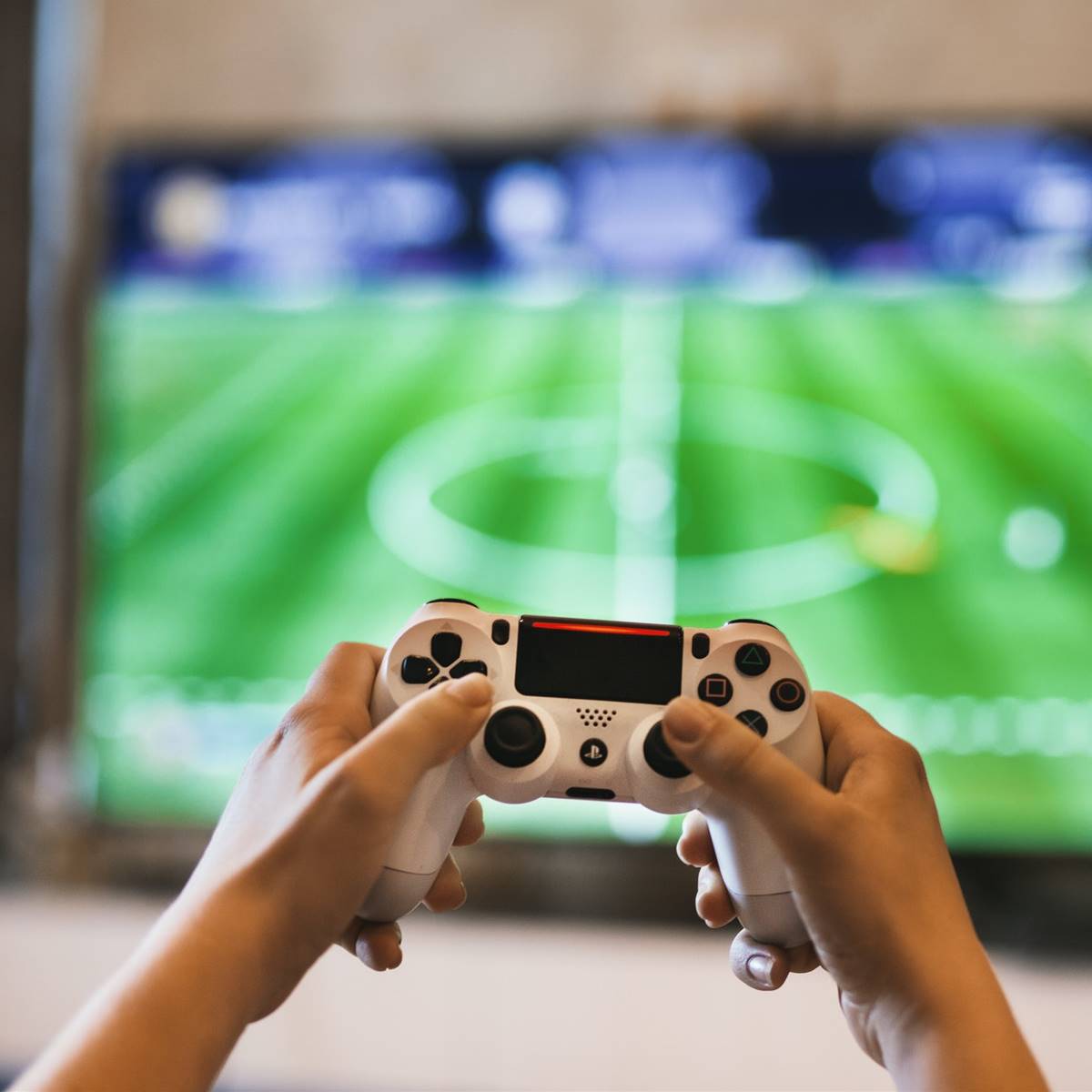 Niño con un mando de consola en la mano y un juego de futbol al fondo