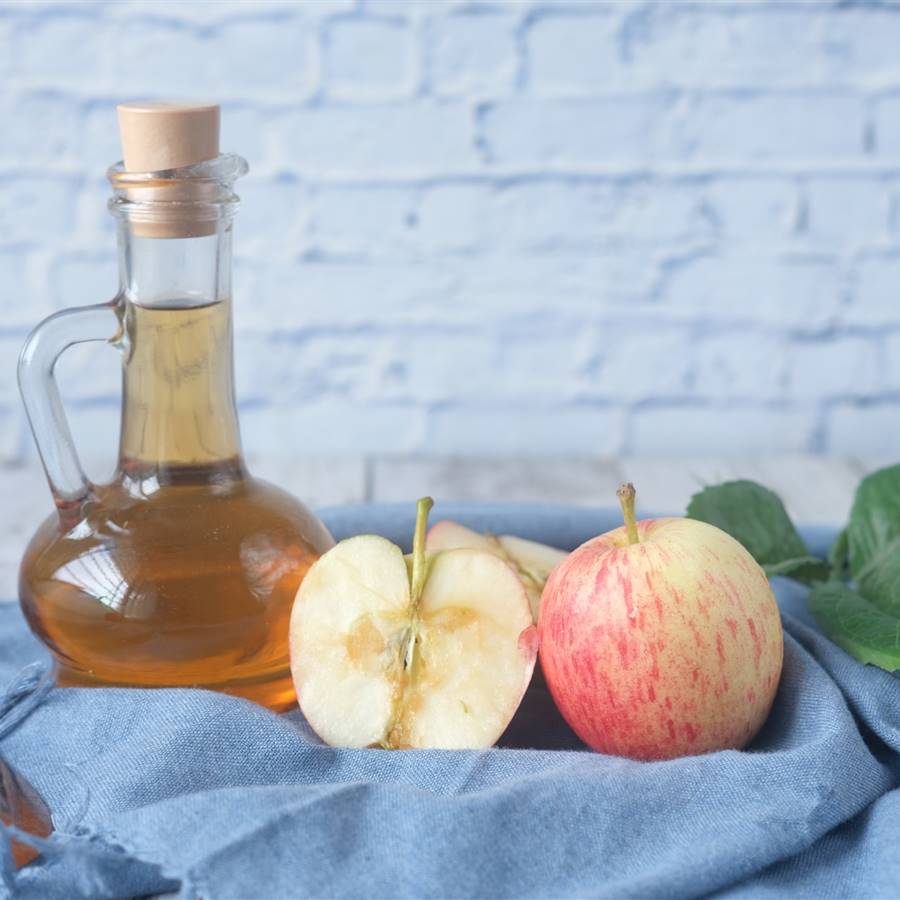 Jarra con vinagre de manzana y manzanas cortadas al lado