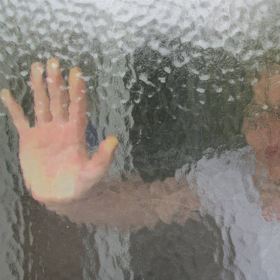 Niño detras de un cristal esmerilado