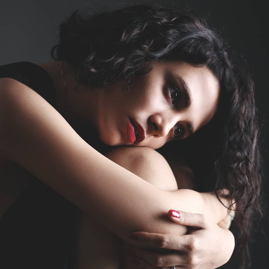 Mujer sentada abrazándose las rodillas