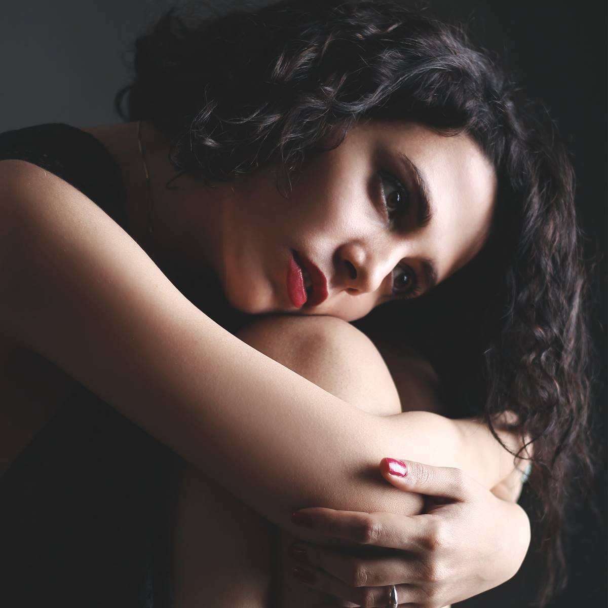 Mujer sentada abrazándose las rodillas
