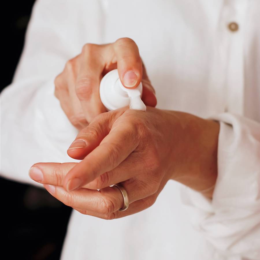 Mujer poniéndose crema de manos