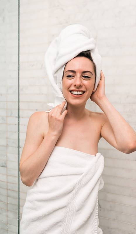 Mujer saliendo de la ducha con turbante y toalla enrollados