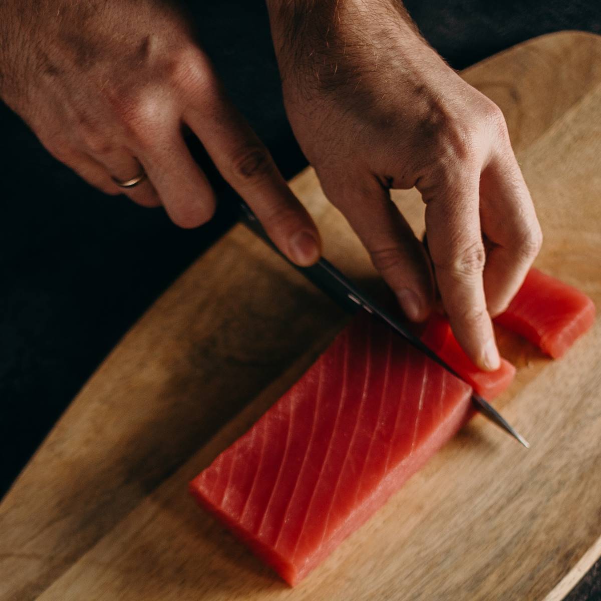 Hombre cortando atún crudo