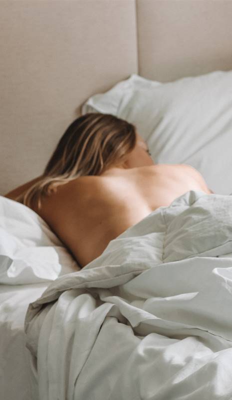 Mujer durmiendo en la cama con la espalda al aire