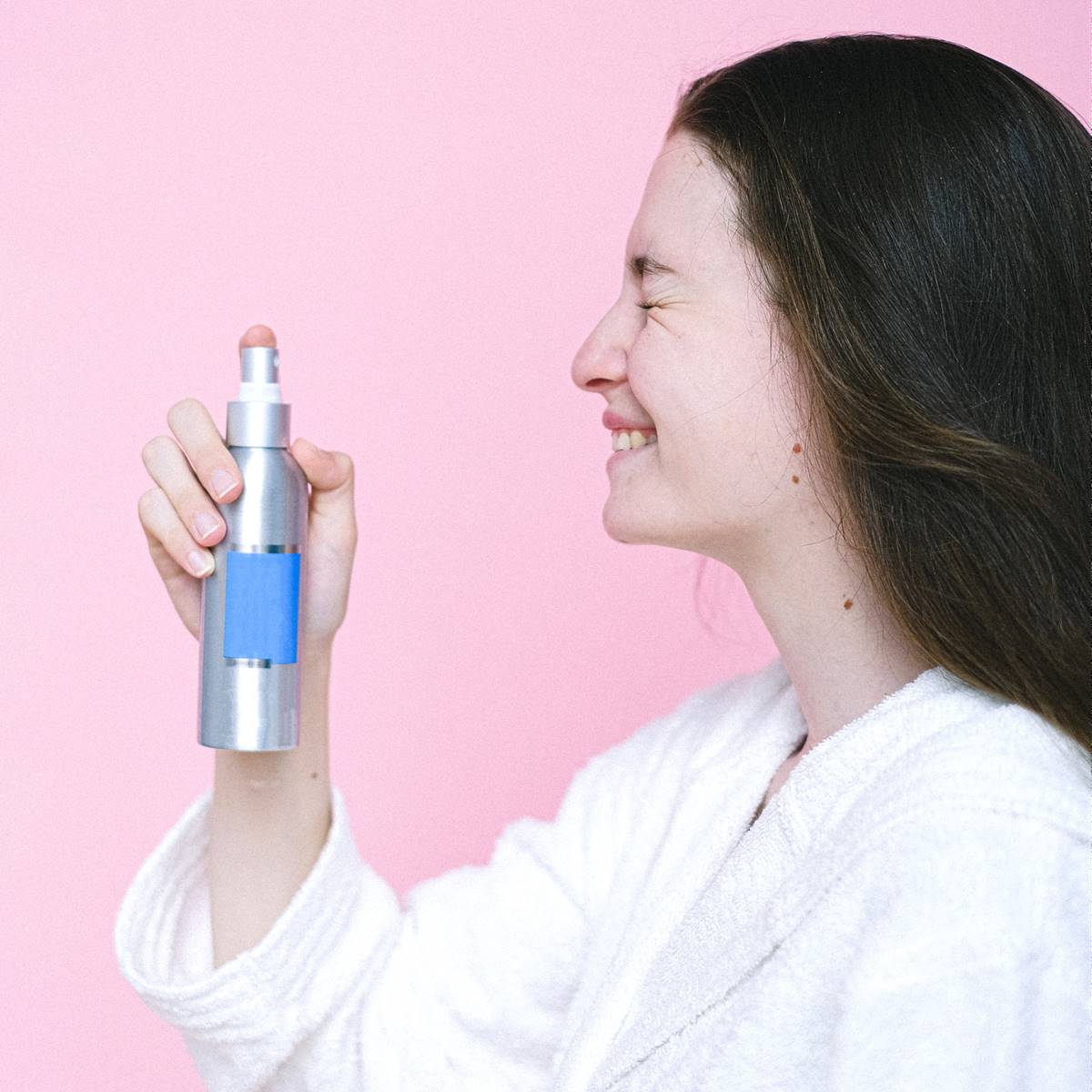 Mujer echándose spray refrescante en la cara