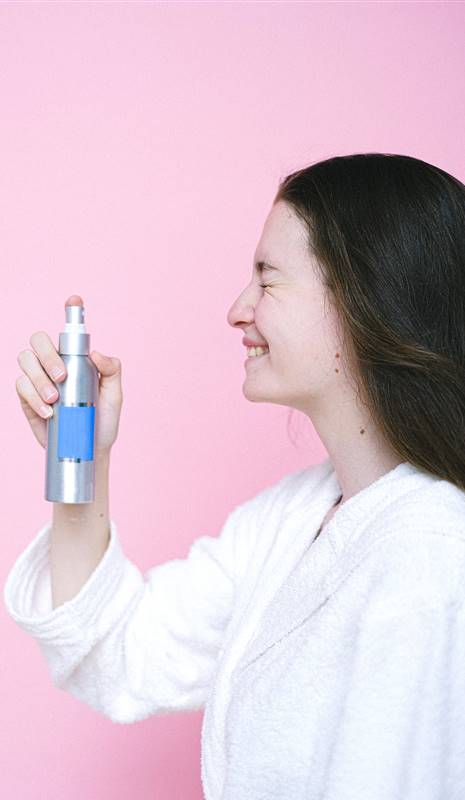 Mujer echándose spray refrescante en la cara