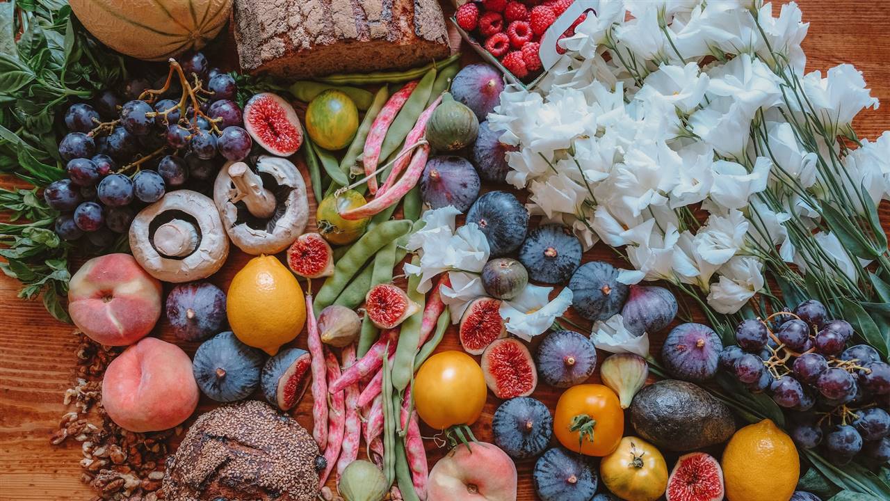 Bodegón con flores, frutas, pan integral y frutos secos