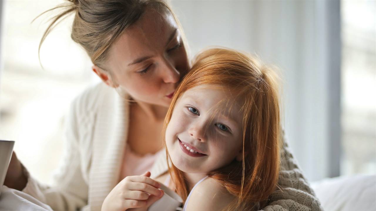 Madre besando y abrazando a su hija