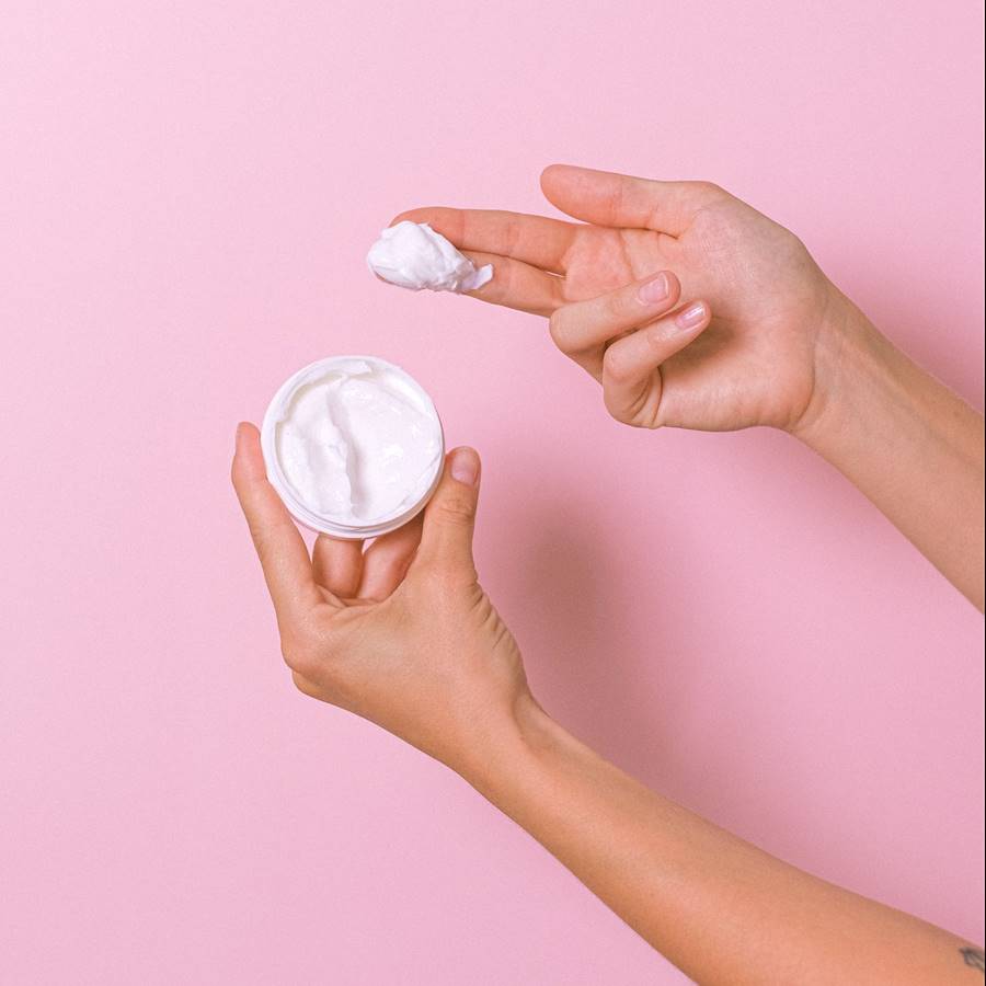 Tarro de crema y mano de mujer con crema