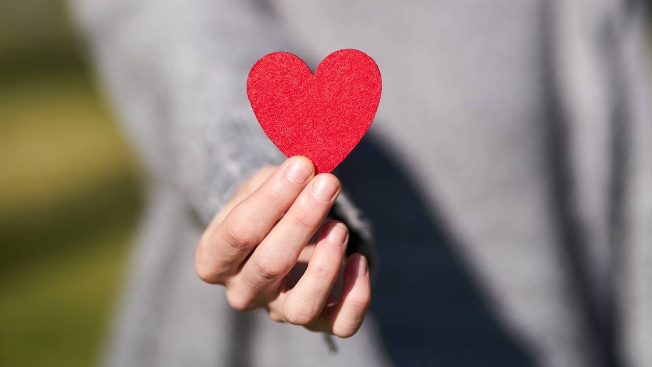 Mujer en segundo plano con un corazón de fieltro en la mano