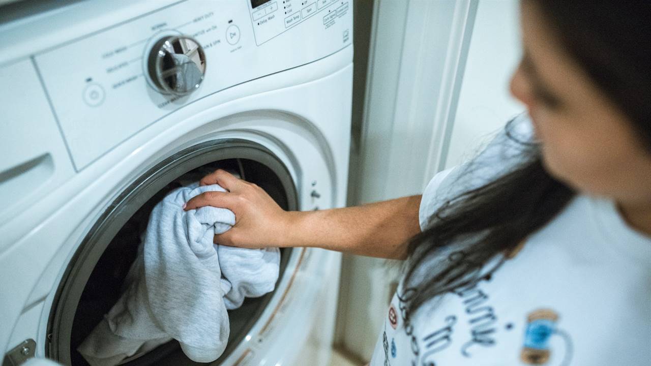 Mujer metiendo ropa en la secadora