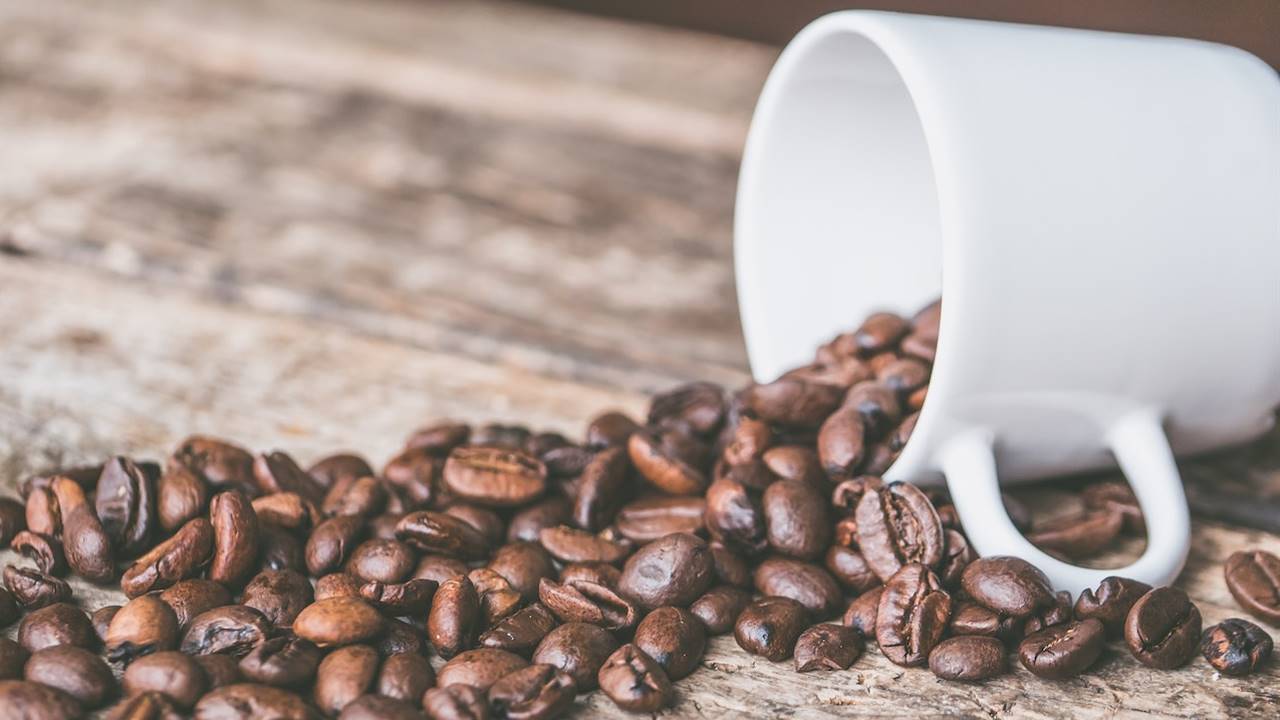 Taza tumbada con granos de cafe