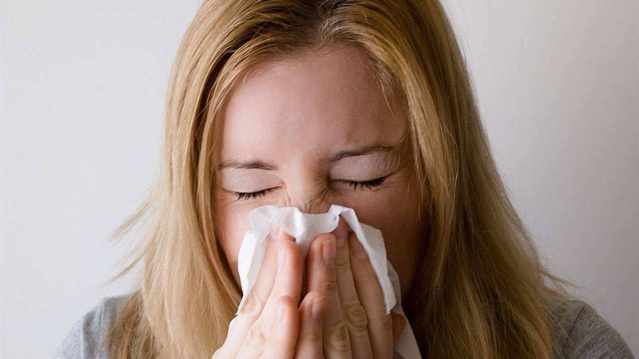 Mujer con un pañuelo estornudando