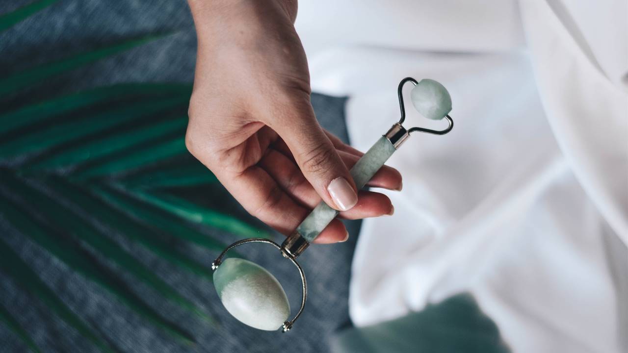 Mujer con masajeador facial de jade en la mano