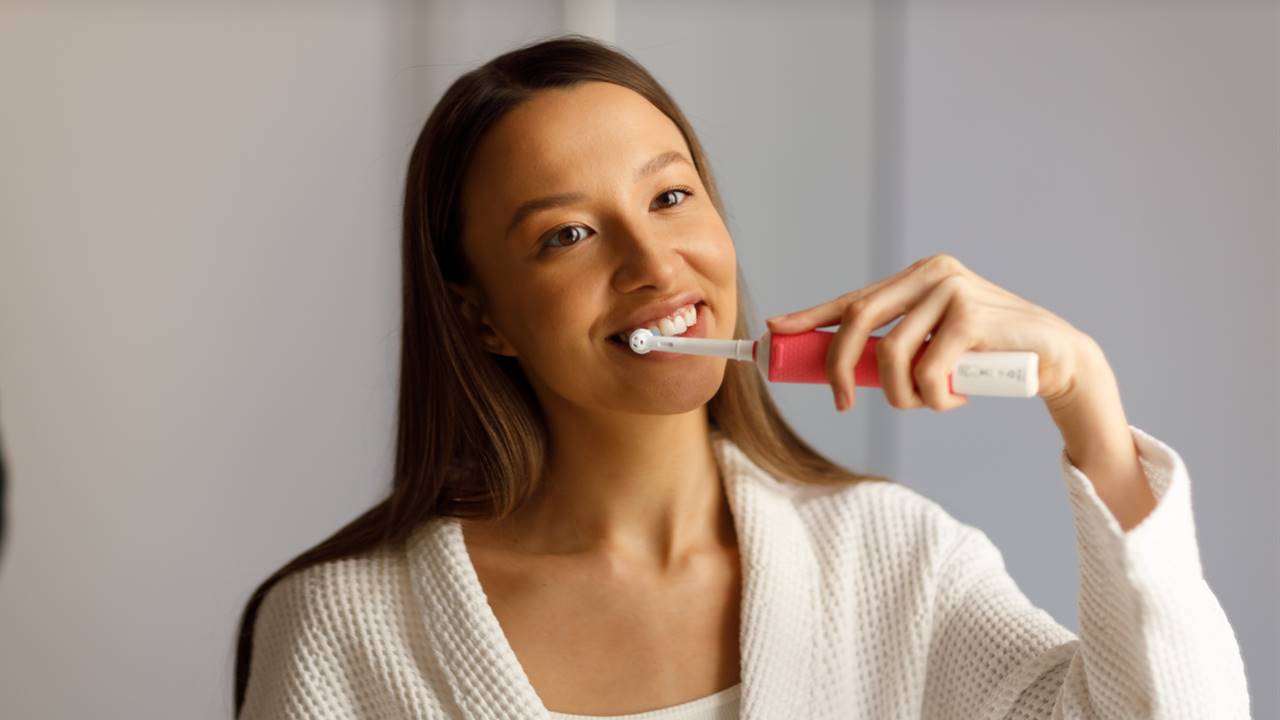 Chica cepillándose los dientes con cepillo eléctrico