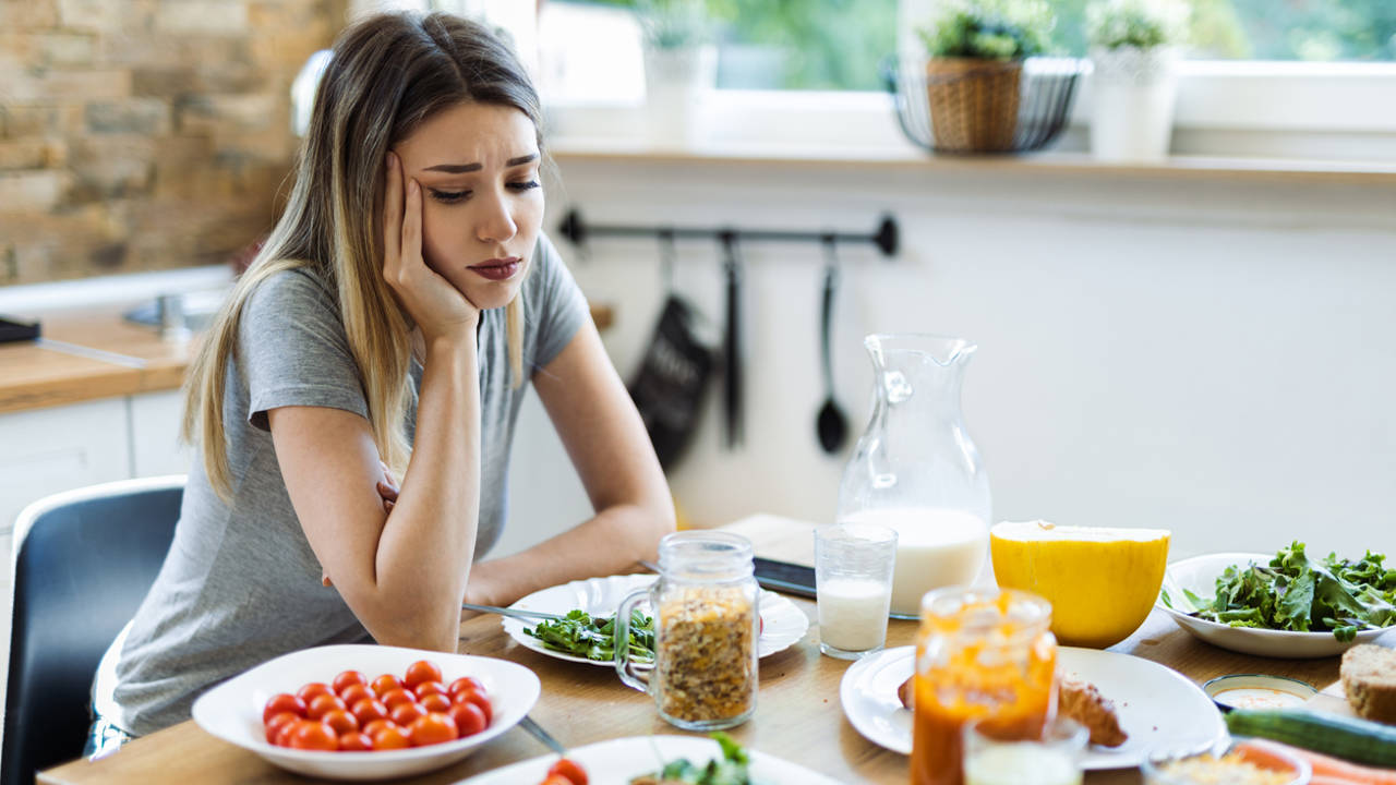 Mujer triste ante platos de comida