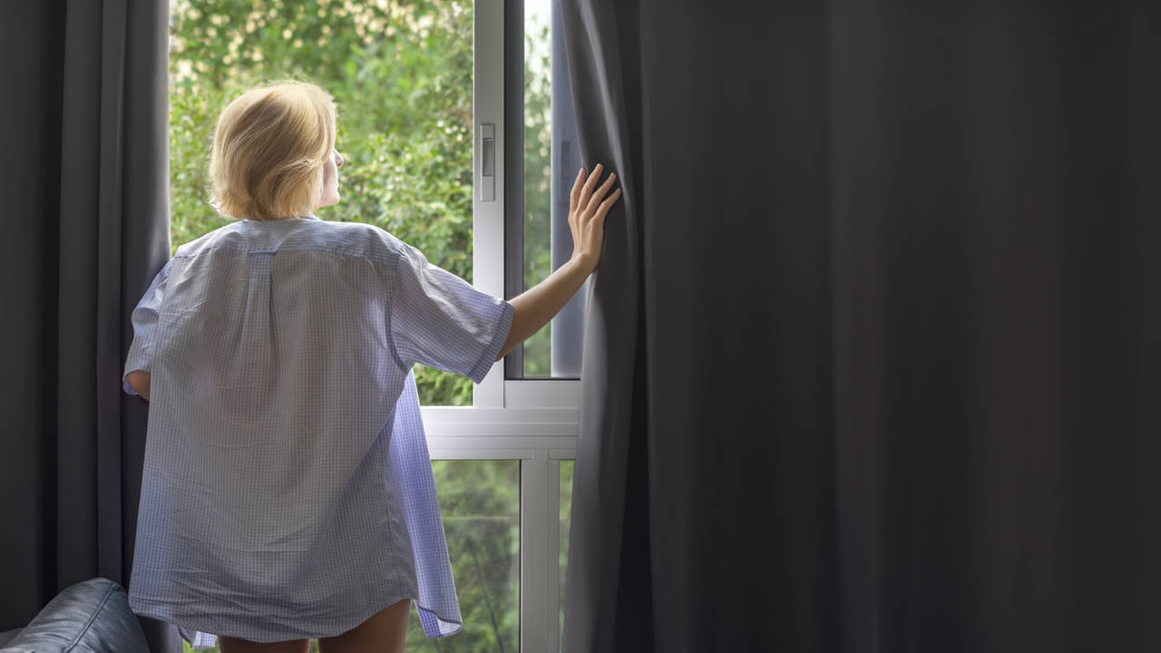 Mujer frente a una ventana abierta