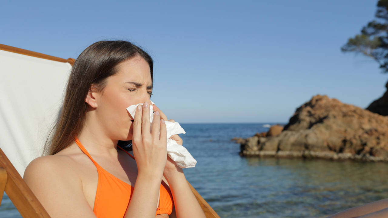 Chica estornudando en la playa