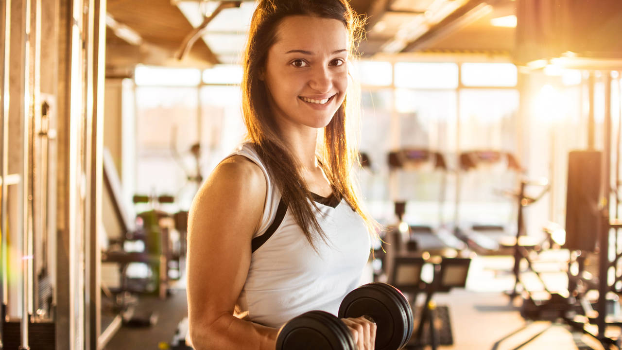 Chica haciendo pesas en el gimnasio
