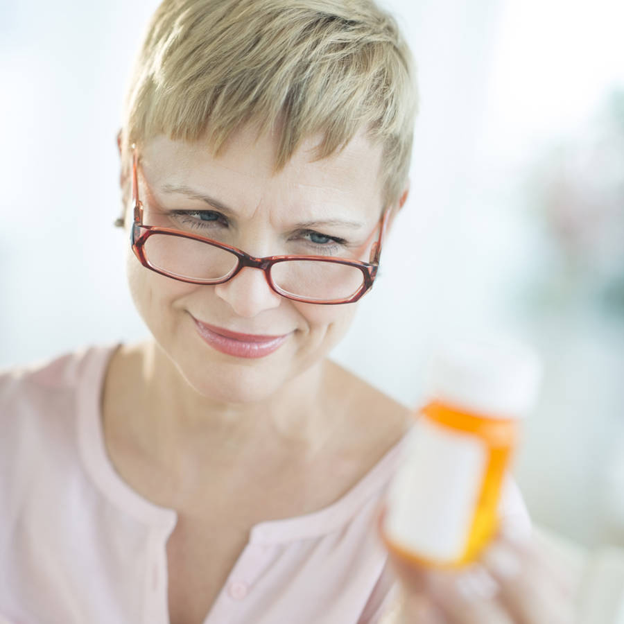 Mujer mirando un frasco de medicamento