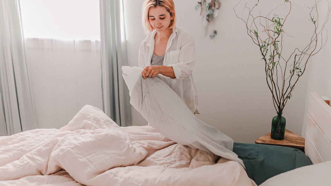 Mujer poniendo ropa de cama limpia